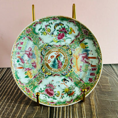 Decorative ceramic plate with intricate designs on a stand against a pink background