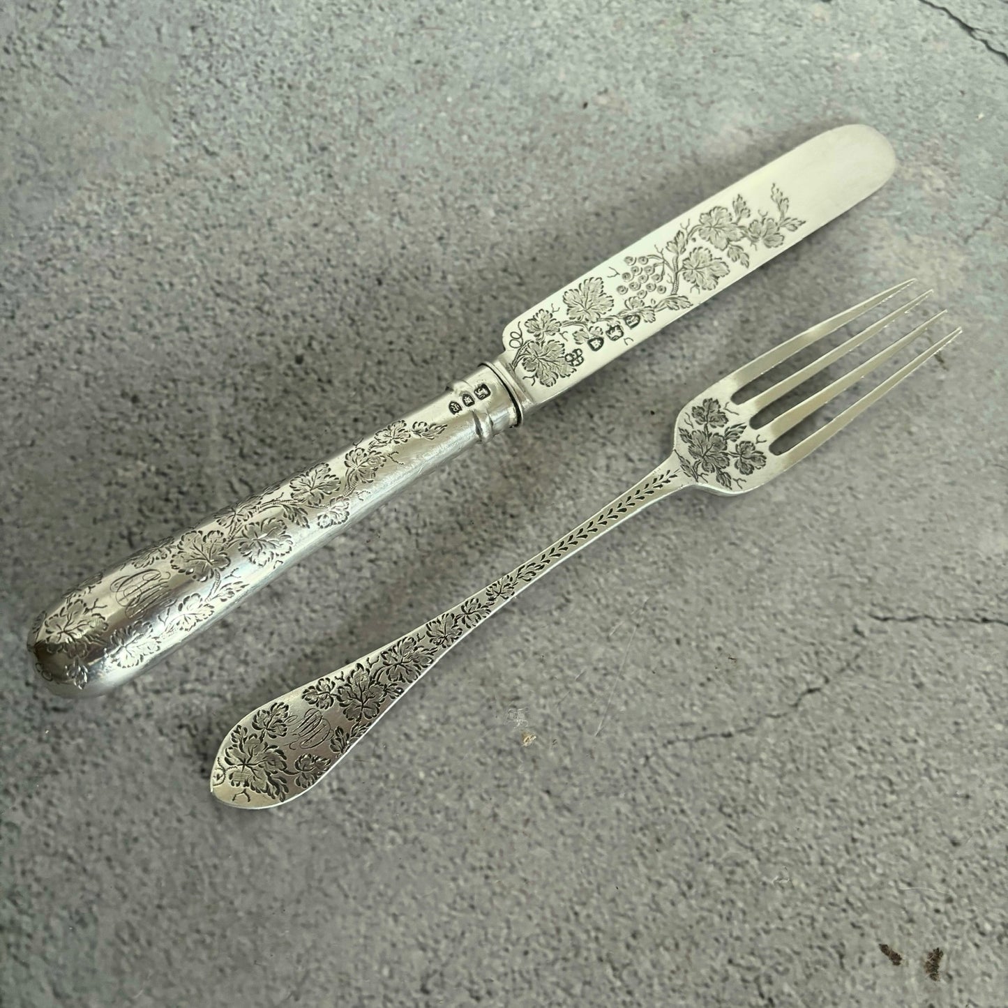 Decorative silver fork and knife set on a gray surface