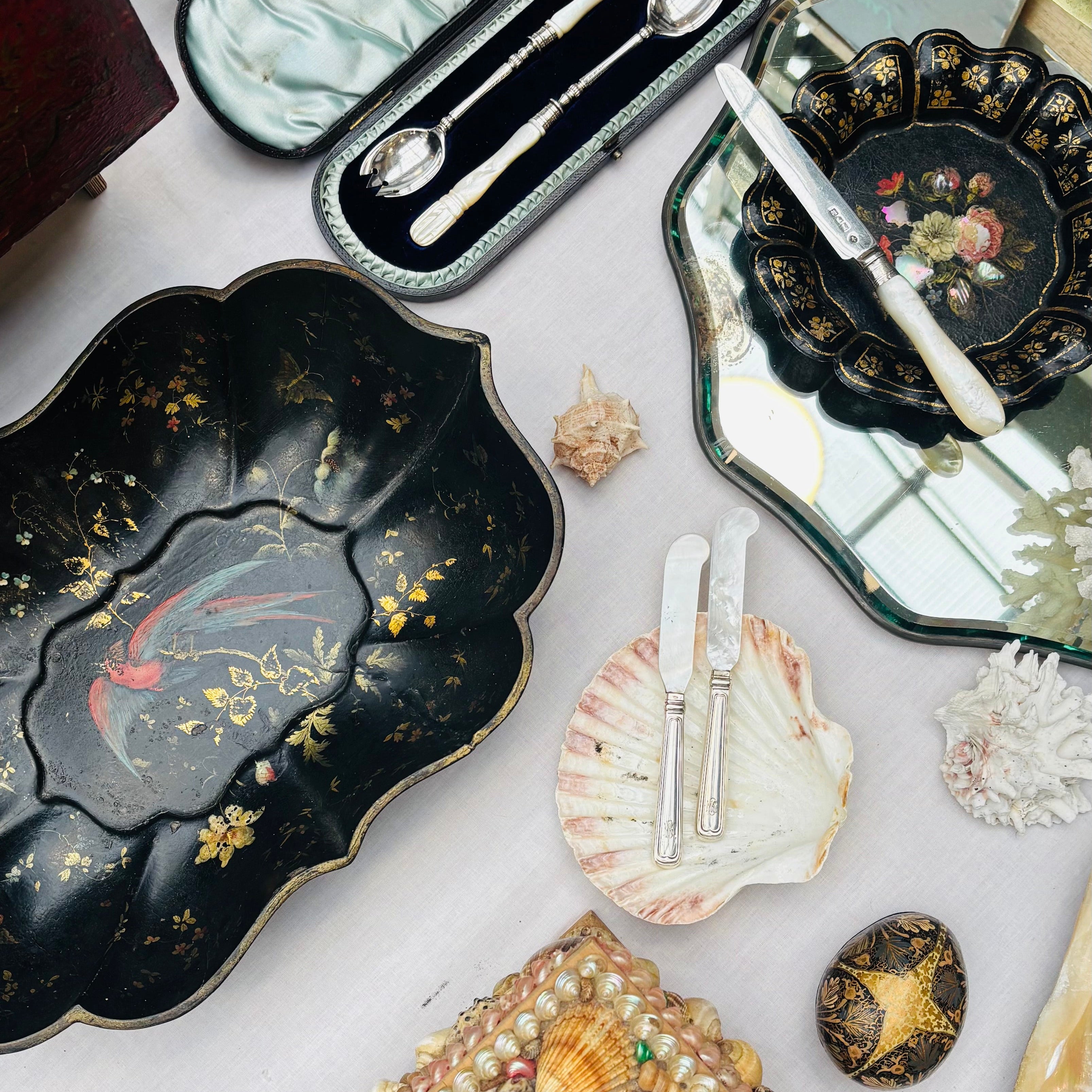 Collection of decorative items including trays, shells, and small boxes on a white surface.