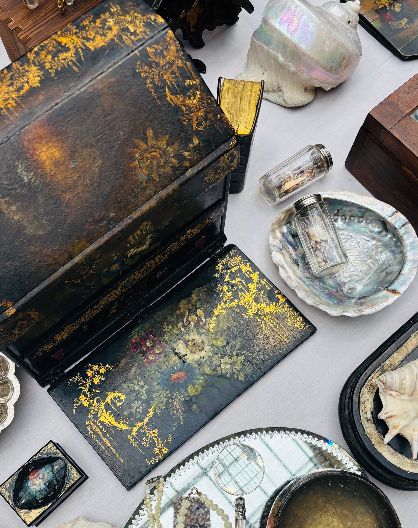 Collection of decorative items including a black lacquer box and shells on a white surface.