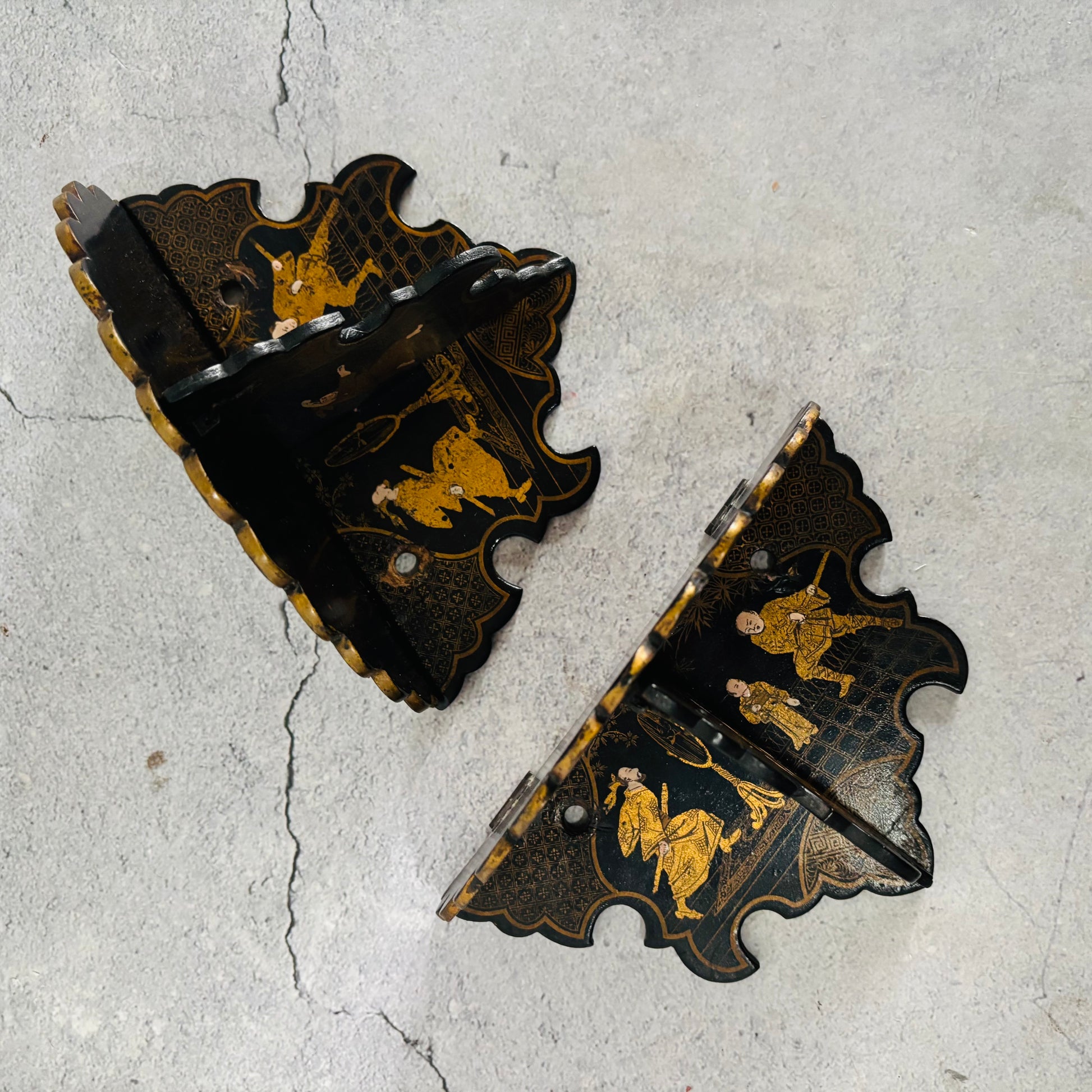 Decorative wall brackets with gold detailing on a textured gray surface