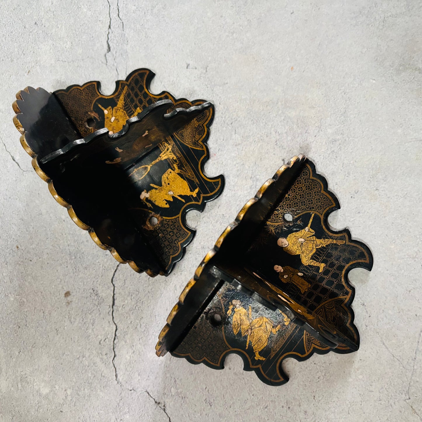 Decorative black and gold wall brackets on a textured gray background