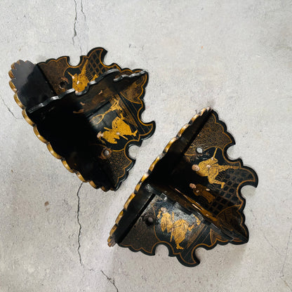 Decorative black and gold wall brackets on a textured gray background