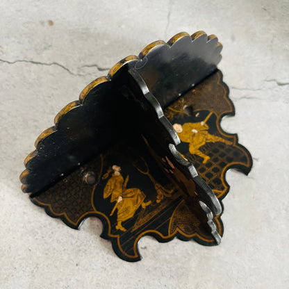Decorative black and gold wall bracket on a textured white background