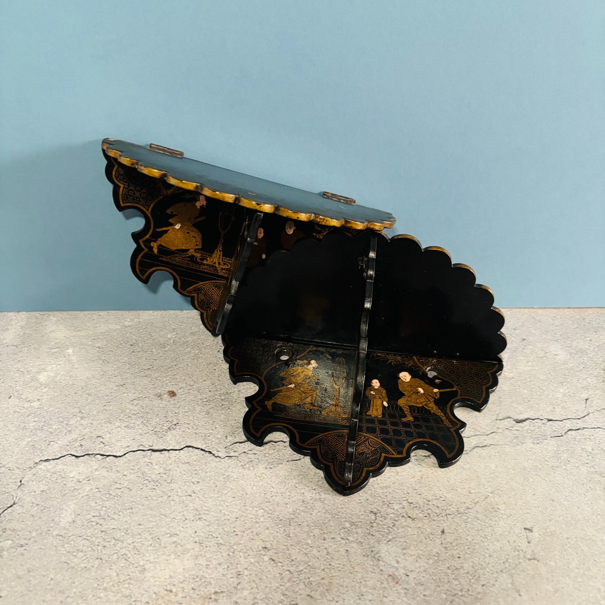 Decorative metal wall bracket on a concrete surface with a light blue wall background