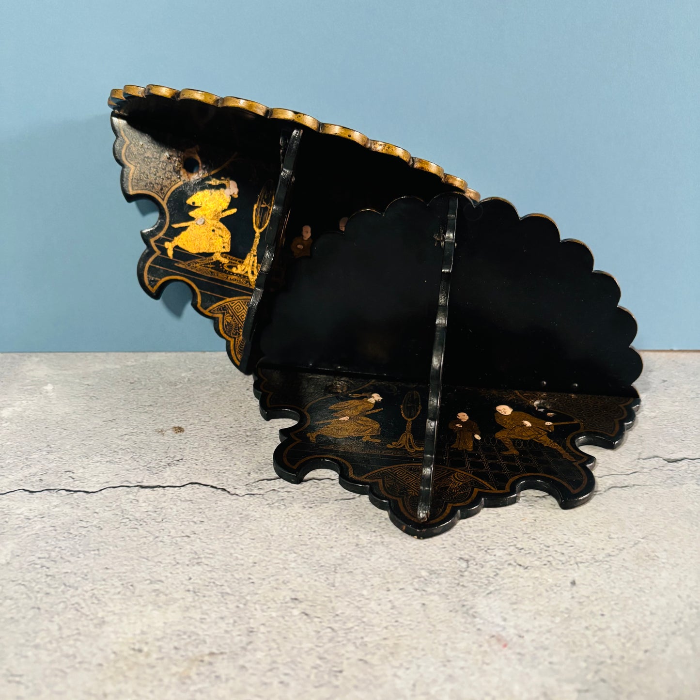 Decorative black and gold wall shelf against a light blue background