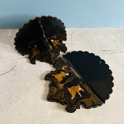 Decorative black and gold wall art piece on a textured surface with a light blue background