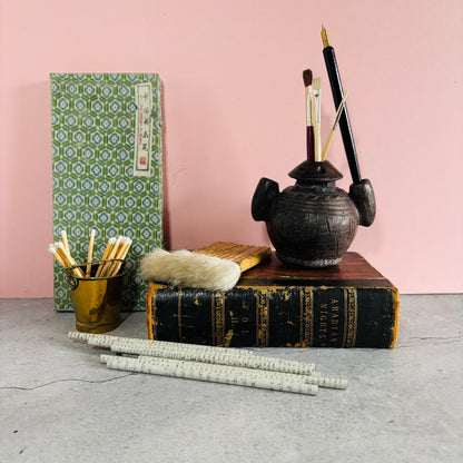 Antique Stationery items including a notebook, inkwell, and quill on a pink background