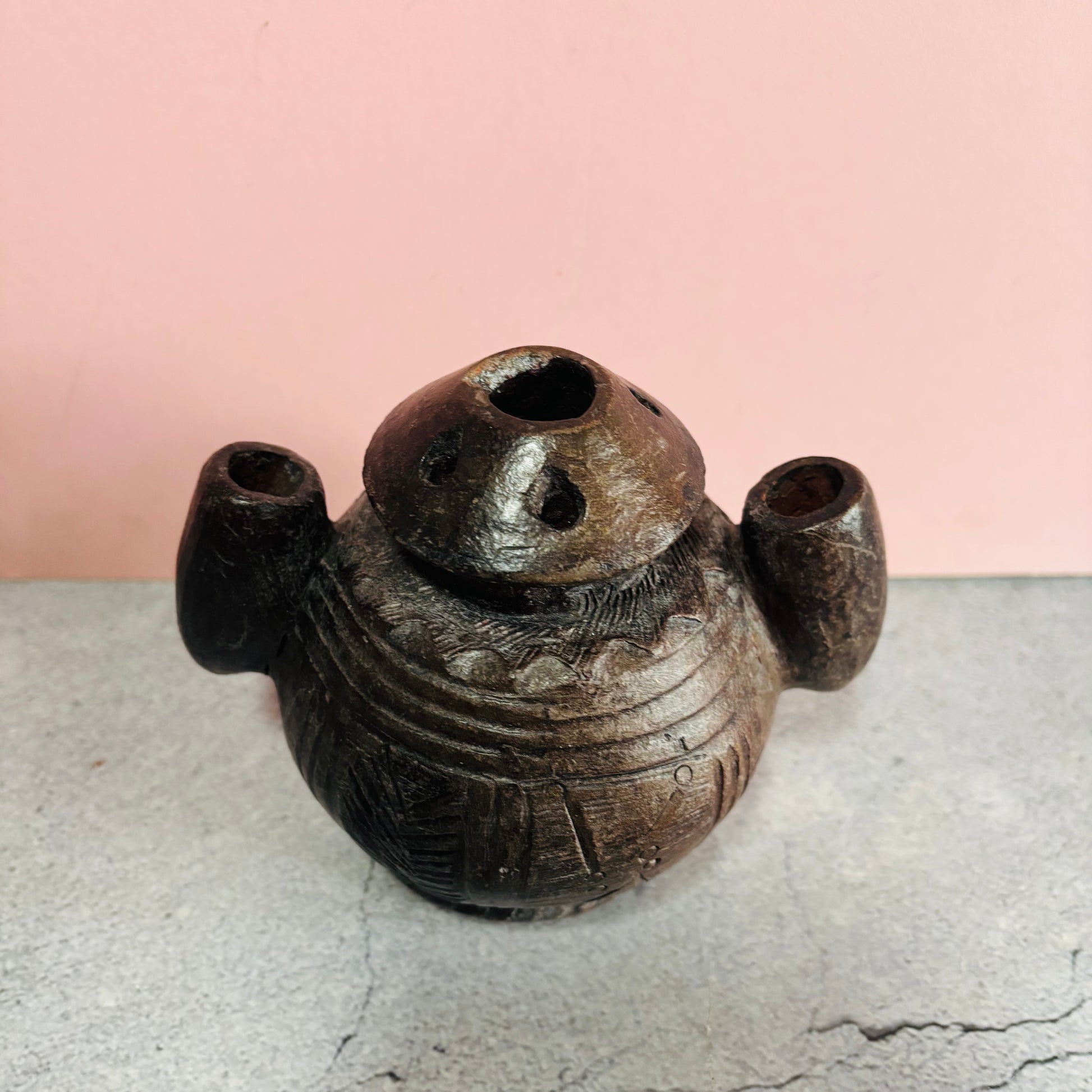 Decorative ceramic vase with unique design on a light gray surface and pink background