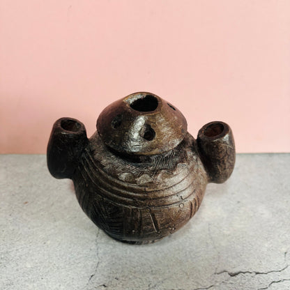 Decorative ceramic vase with unique design on a light gray surface and pink background