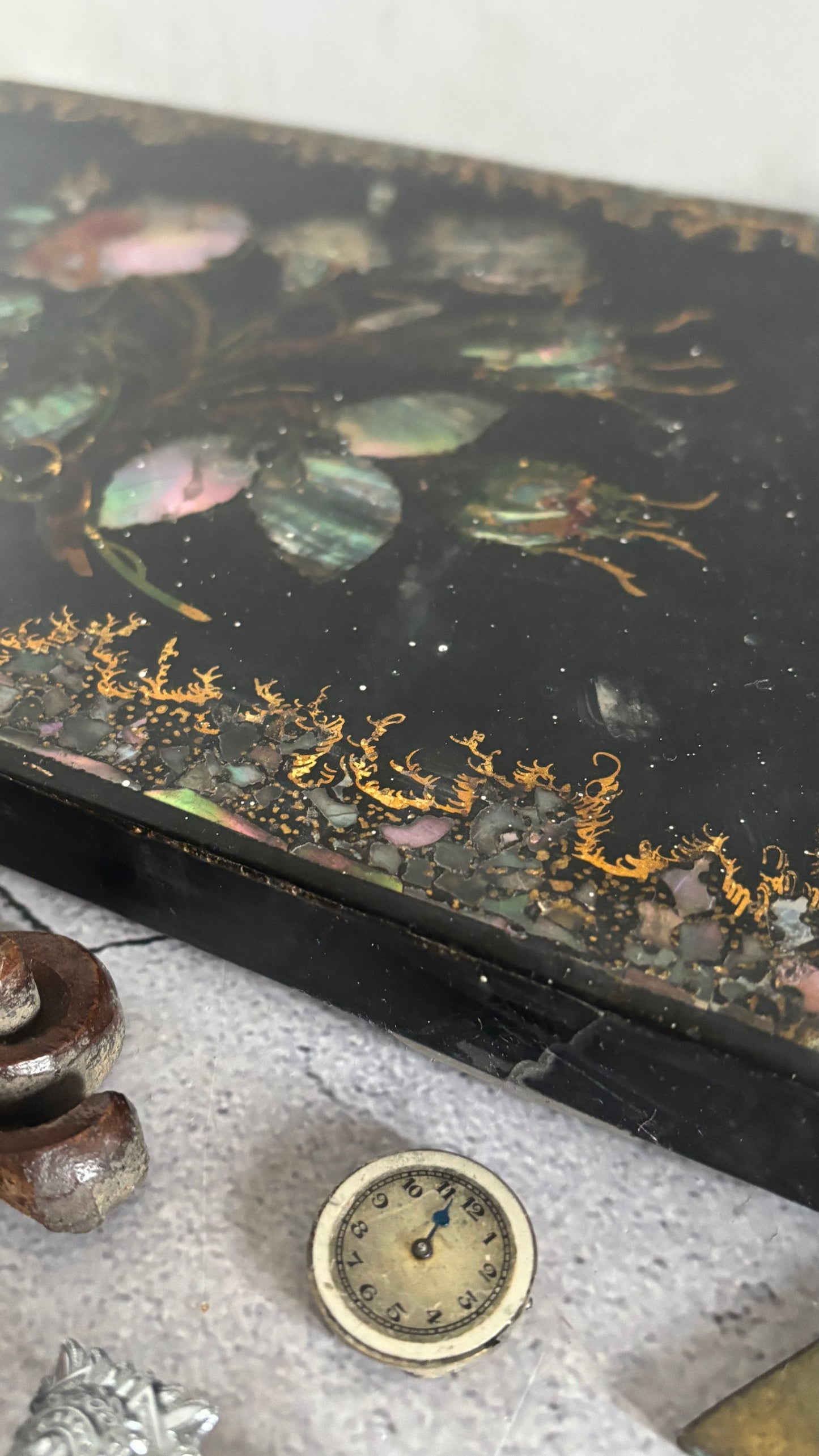 Decorative box lid with floral design and gold accents on a textured surface.