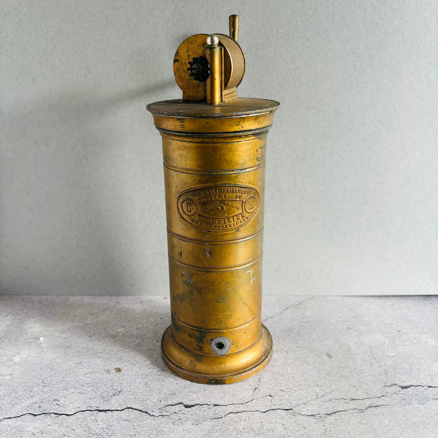 Vintage brass Antique Gynaecological Vaginal Irrigation Pump on a grae surface with a neutral background