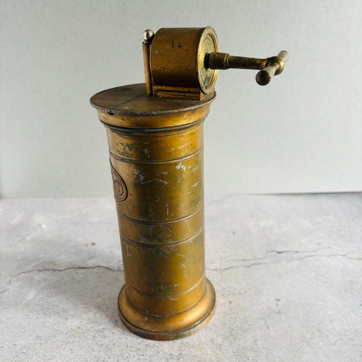 Vintage brass Antique Gynaecological Vaginal Irrigation Pump on a textured surface with a neutral background