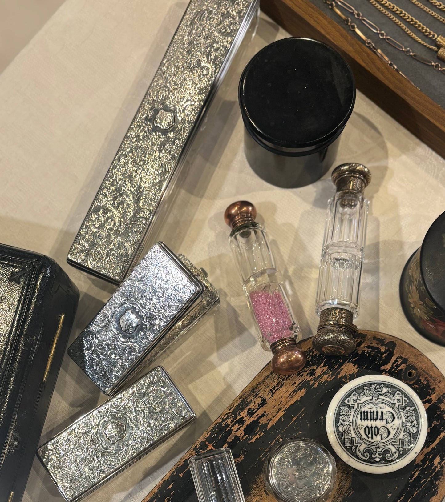 Collection of vintage-style items including a black container with decorative elements on a textured surface.