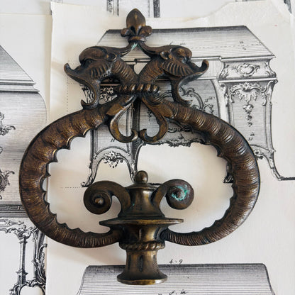Decorative metal wall piece with intricate design on a vintage architectural background