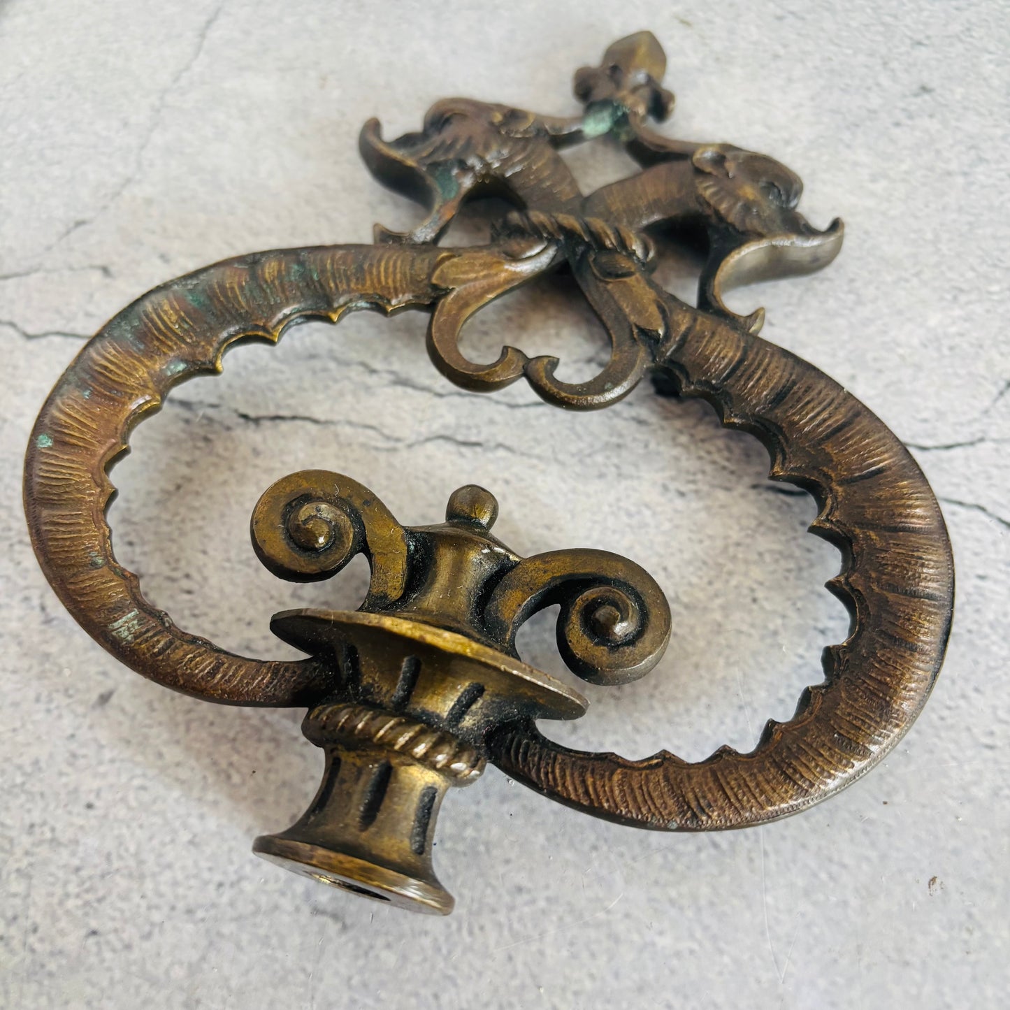 Decorative bronze handle with intricate design on a textured surface