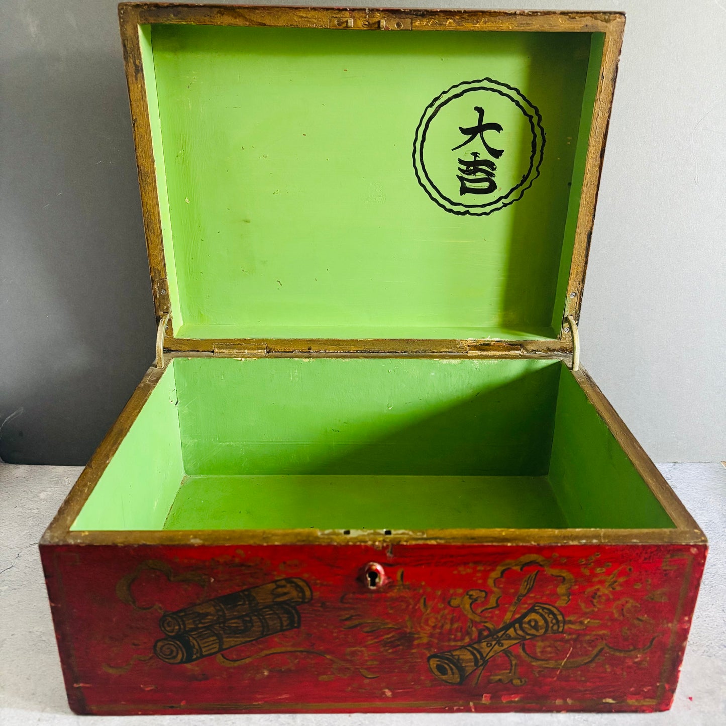 Open wooden box with green interior and decorative patterns on a plain background