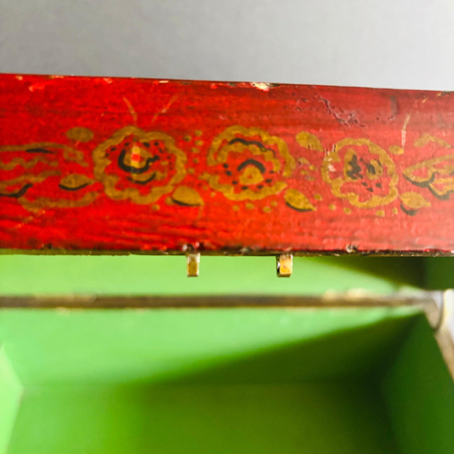 Decorative red box with gold floral patterns on a green surface