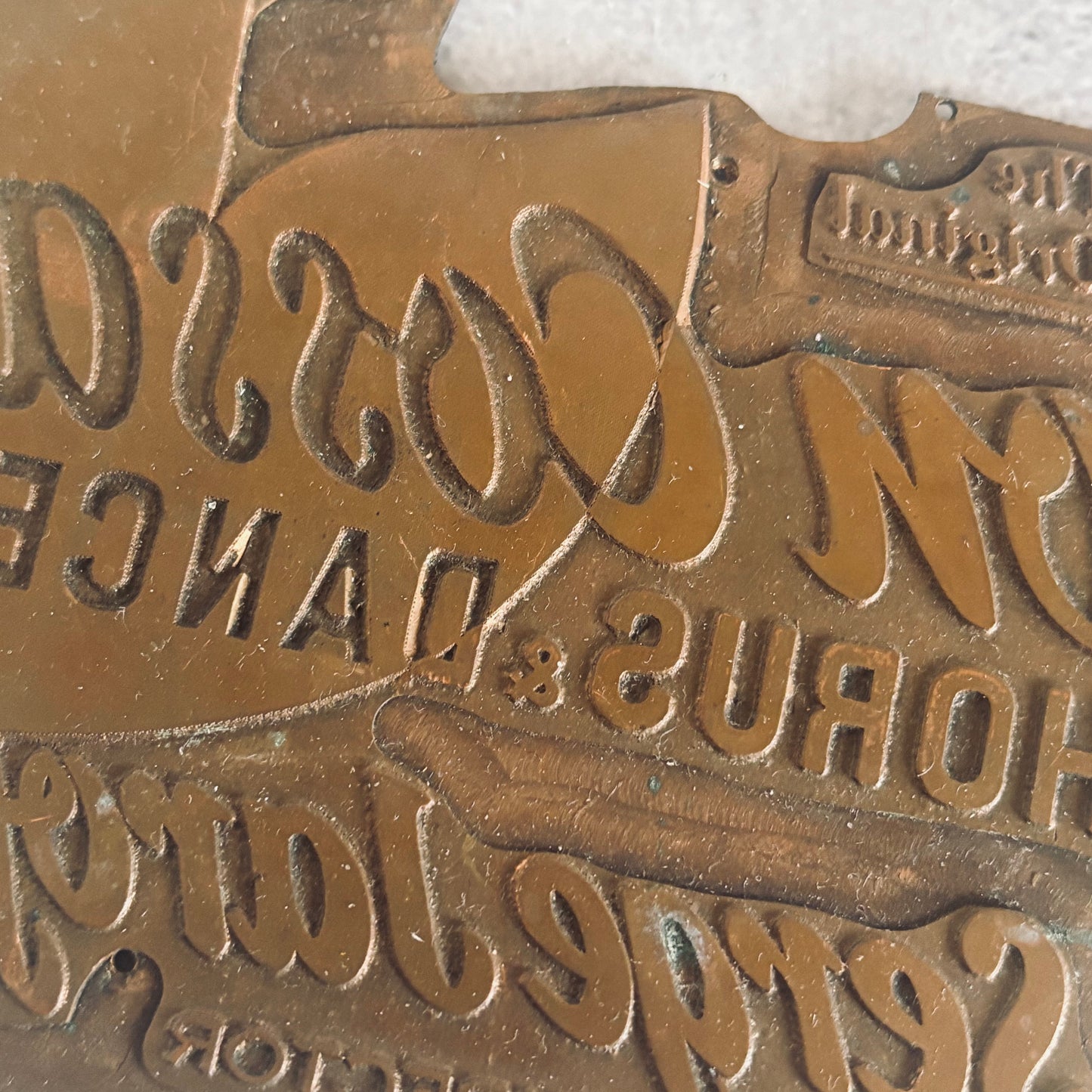 Close-up of a bronze sign with embossed text and logo