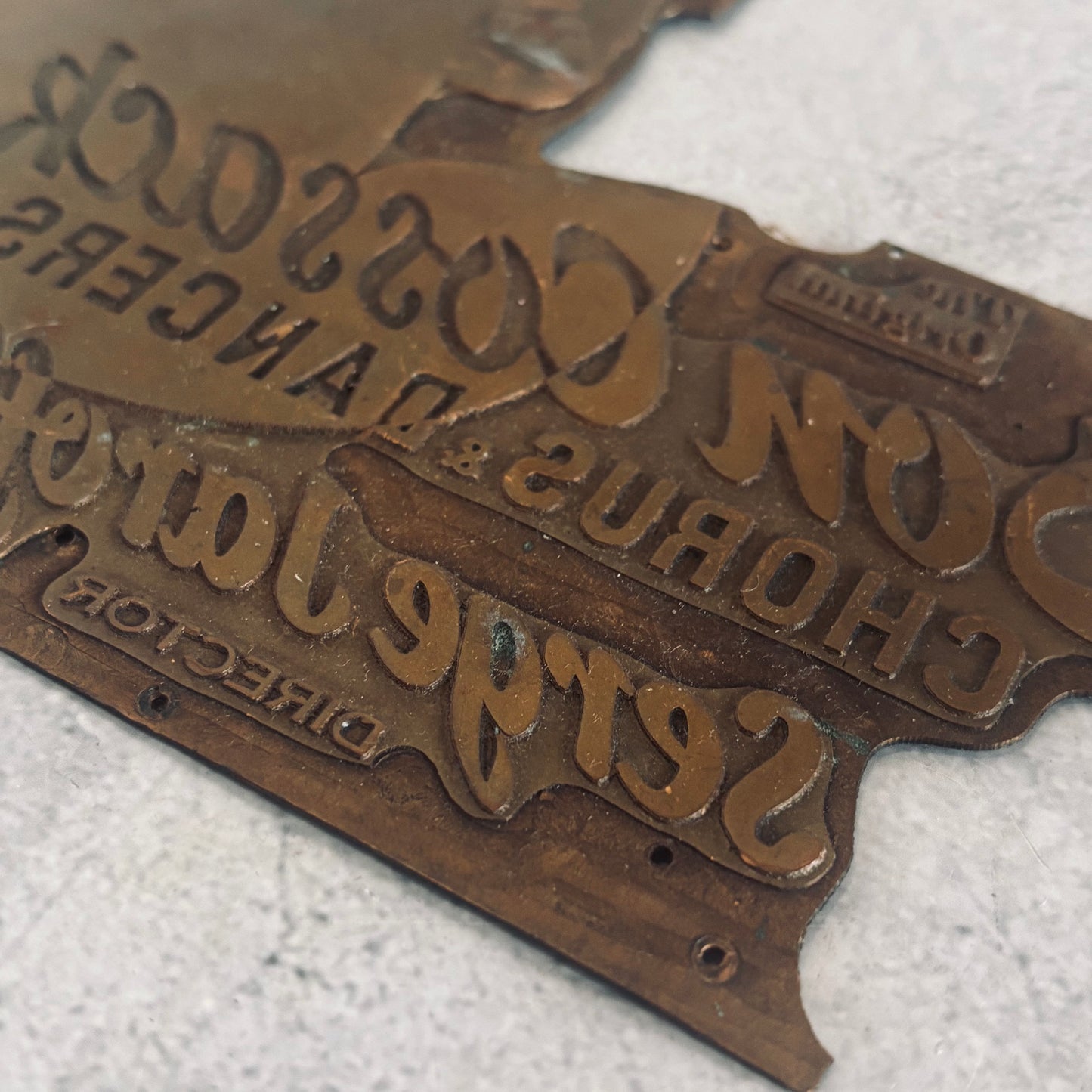Close-up of a vintage metal sign with engraved text on a white background