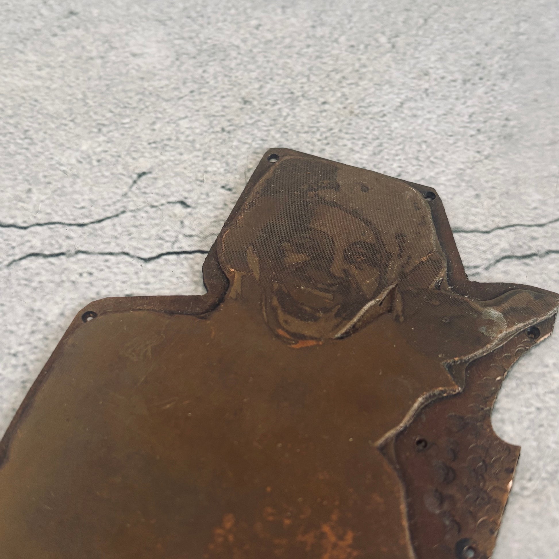 Metal plaque with a portrait on a textured surface