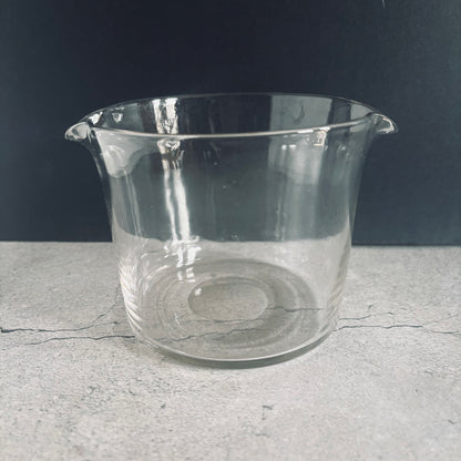 Clear glass beaker on a gray surface with a dark background