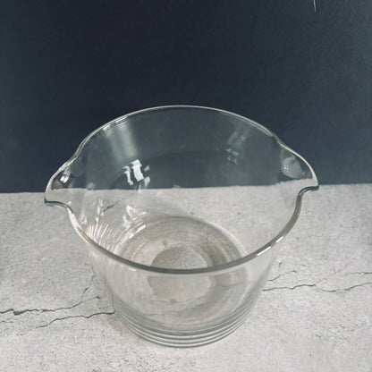 Clear glass beaker on a gray surface with a dark background