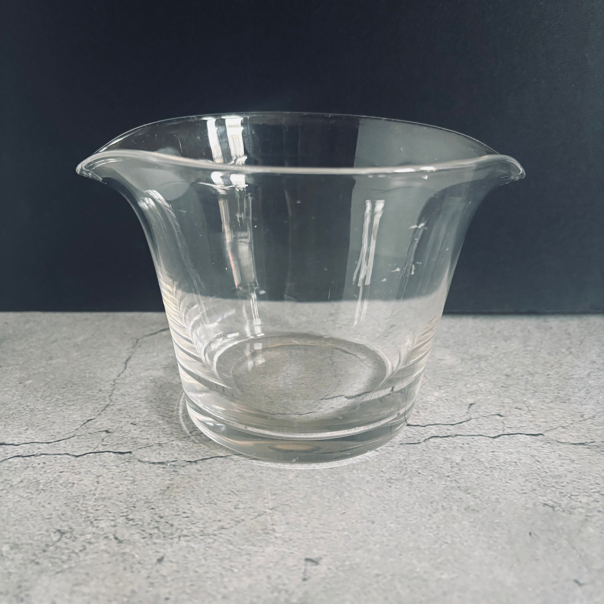 Clear glass vase on a gray surface with a dark background