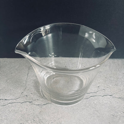 a clear glass antique cooling rinser on a textured gray surface with a dark background