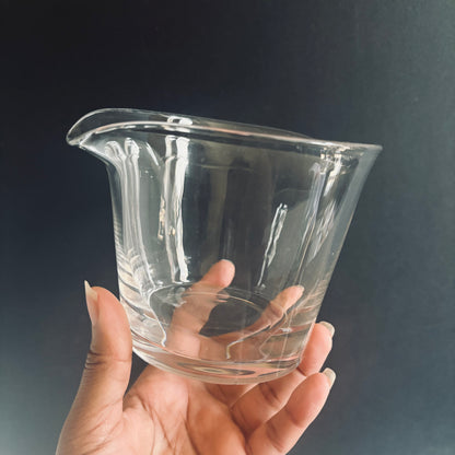 Clear glass rinser held in a hand against a dark background