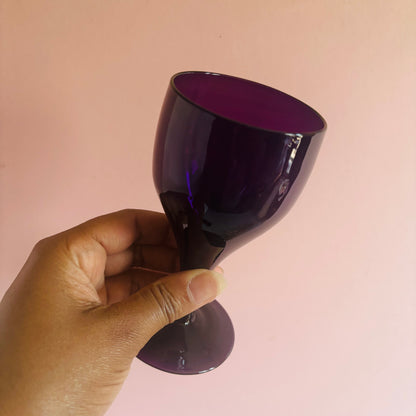 Hand holding a dark purple object against a pink background