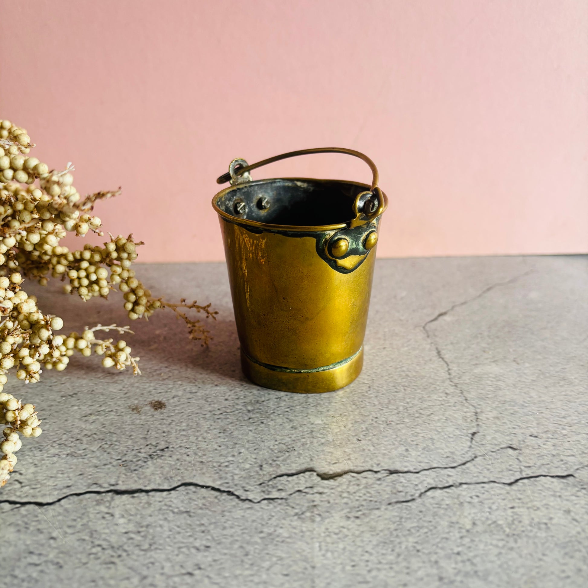 Edwardian Novelty Brass Bucket Vesta
 on a stone surface against a pink wall