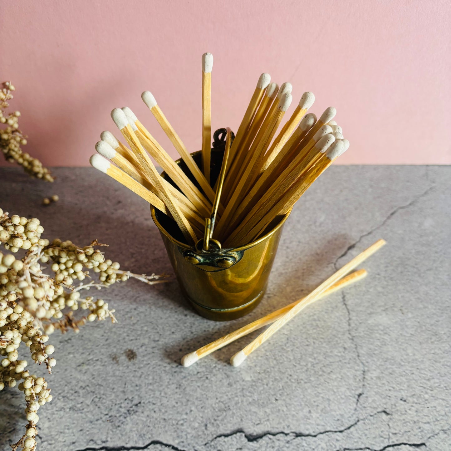 Matchsticks in a holder on a textured surface with a pink background