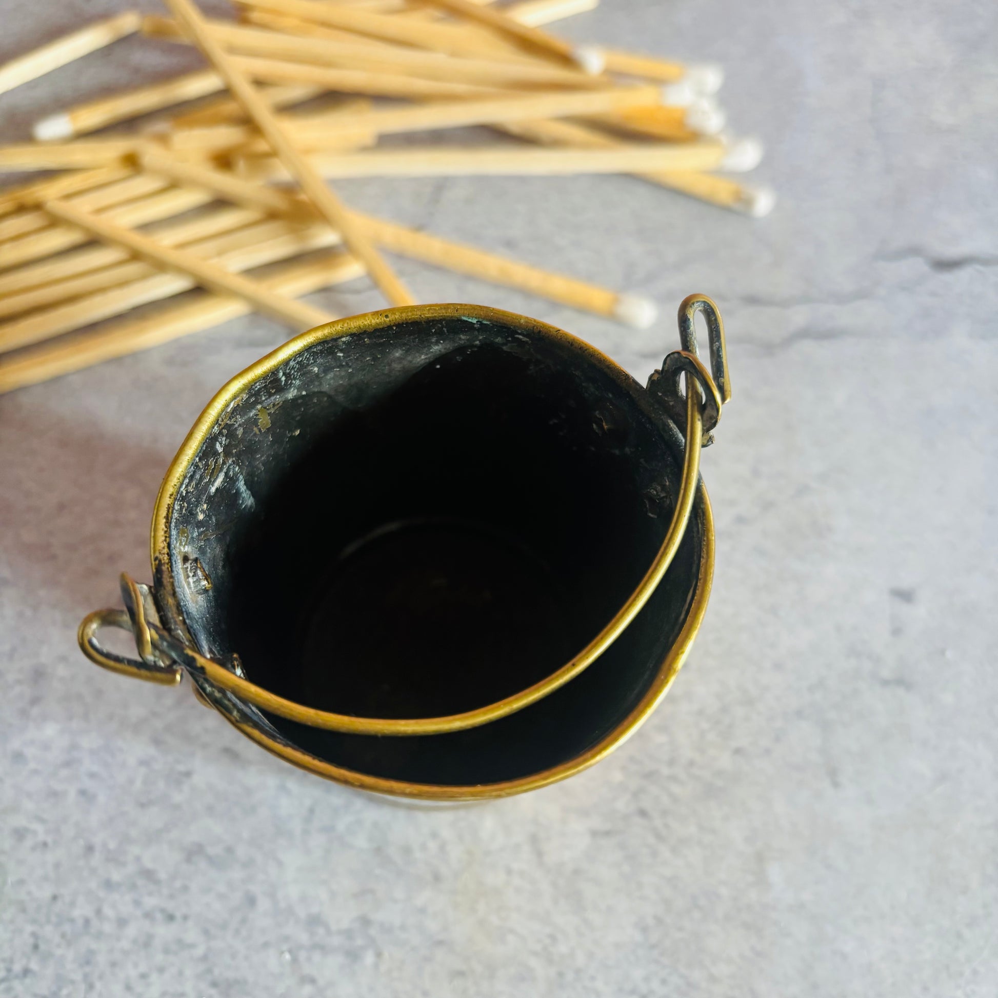 Antique Novelty Brass Bucket Vesta on a stone surface 