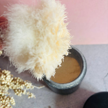 Cosmetic product with a fluffy applicator on a pink background