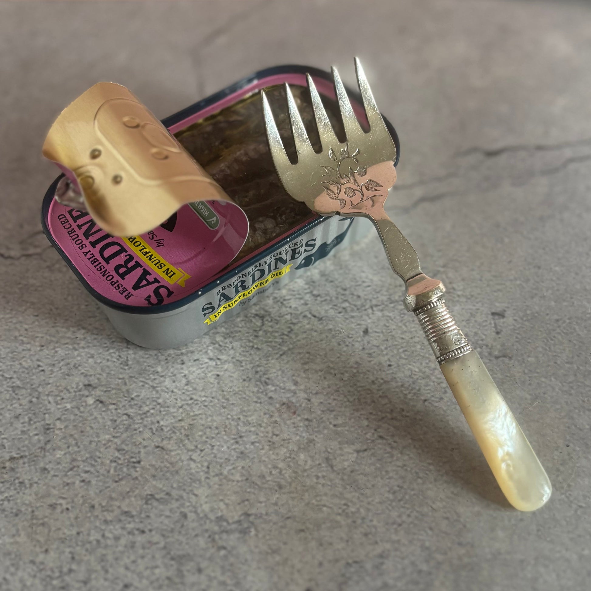 Vintage-style fork and spoon set on a can with a pink background