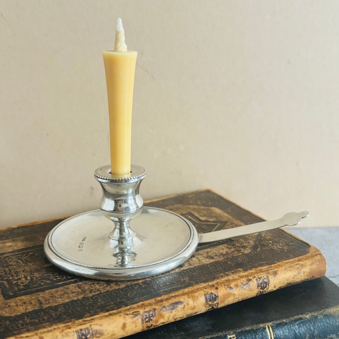 Silver candle holder with a yellow candle on an old book