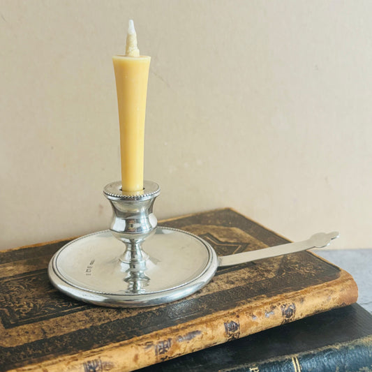 Silver candle holder with a yellow candle on an old book
