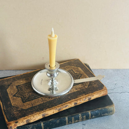 Candle in a silver holder on top of two old books with a plain background