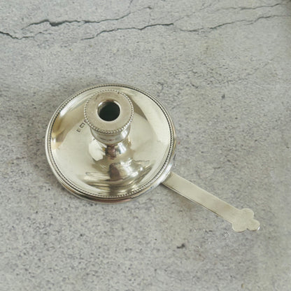 Silver candle holder with a handle on a gray surface