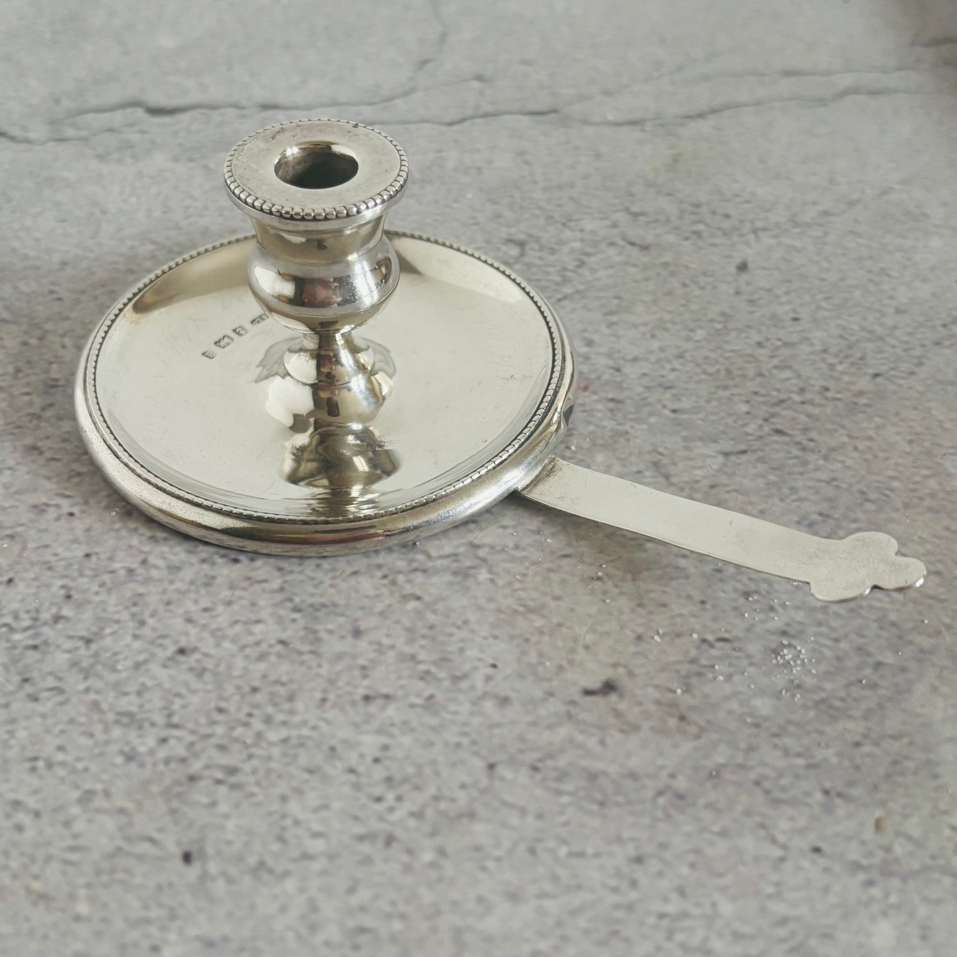 Silver candle holder with a spoon on a gray surface