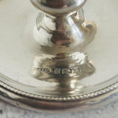 Close-up of a silver chamberstick with engraved hallmarks on a light background