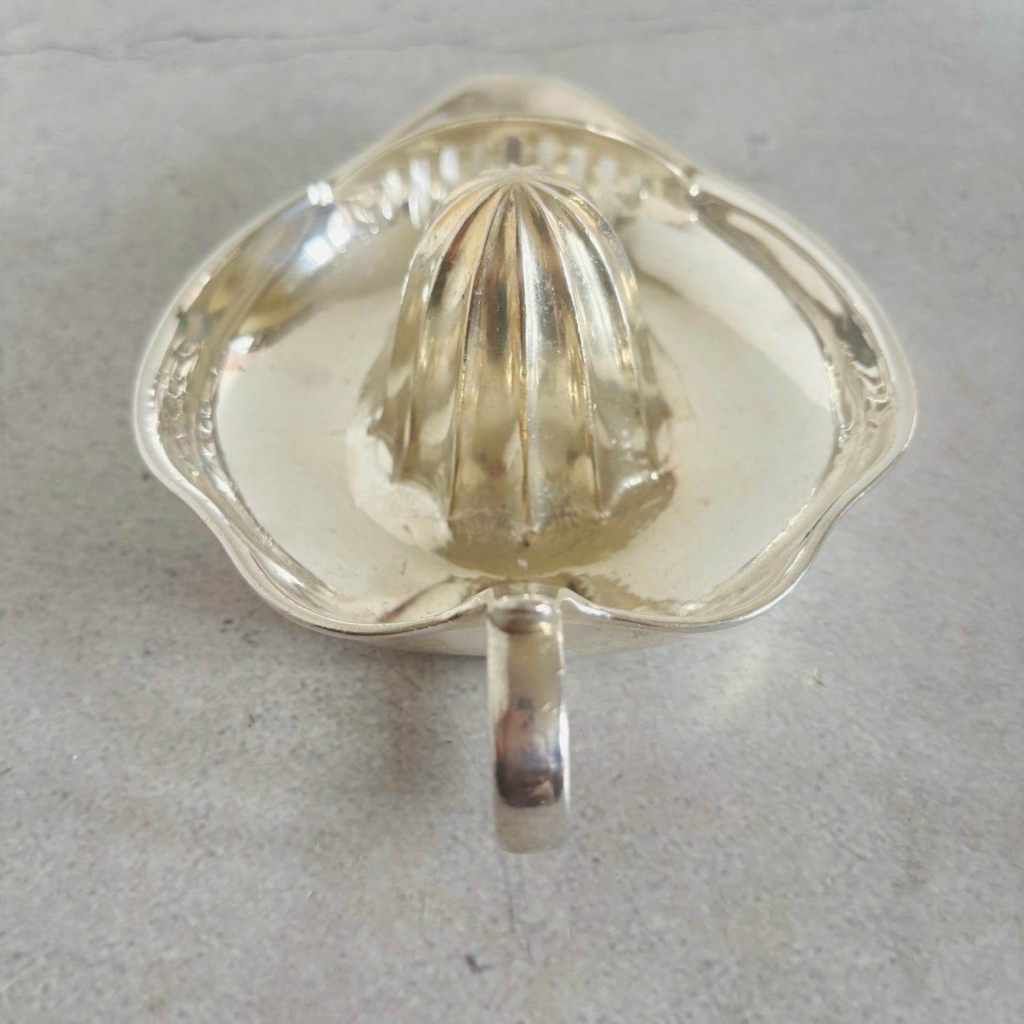 Clear metal citrus juicer on a gray background