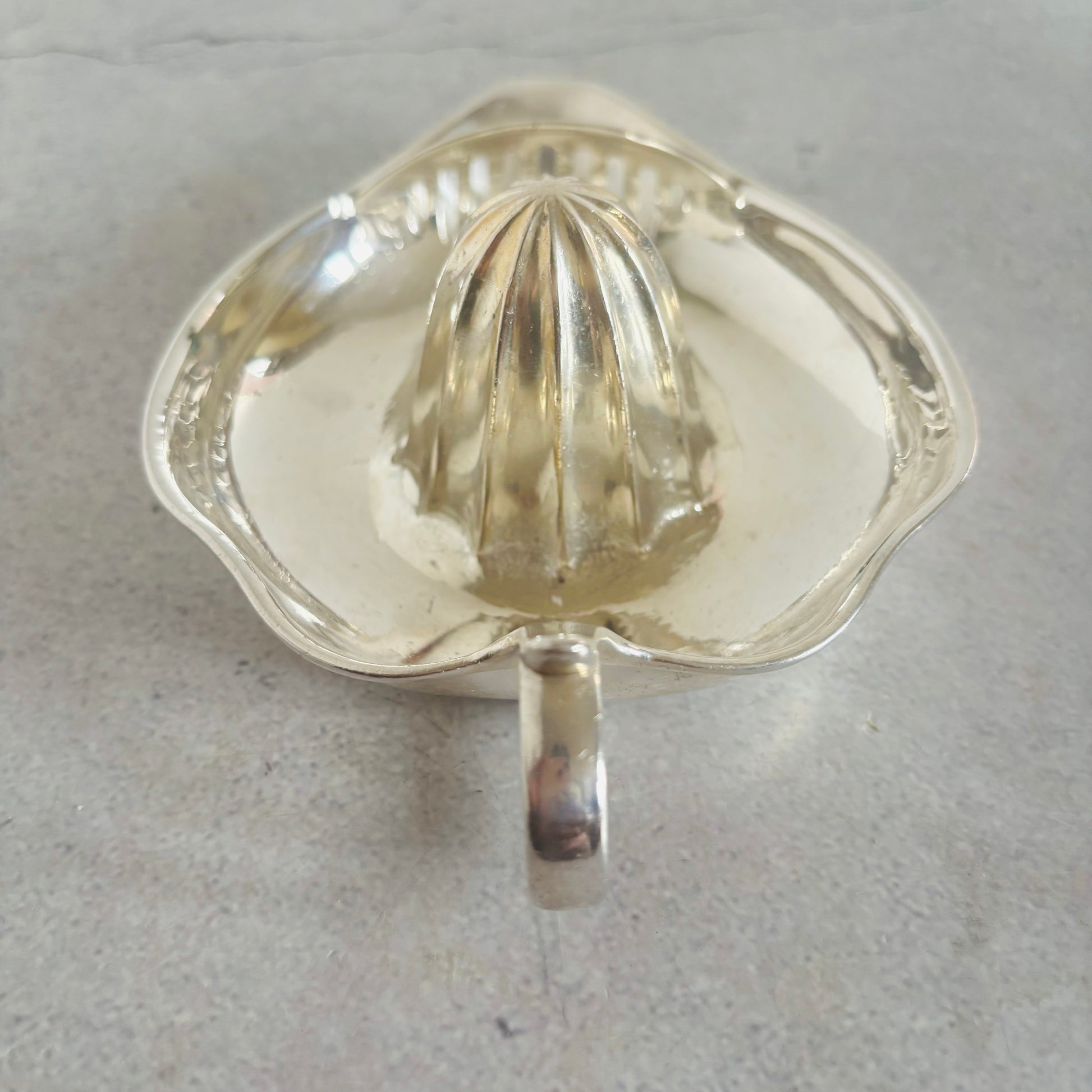 Clear metal citrus juicer on a gray background