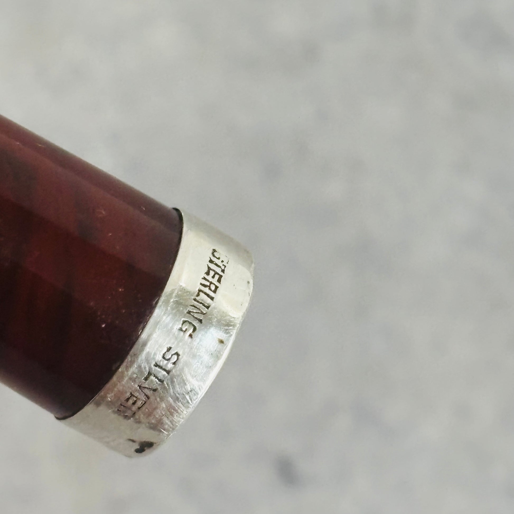 Close-up of a silver ring with 'Sterling Silver' engraving on a gray background