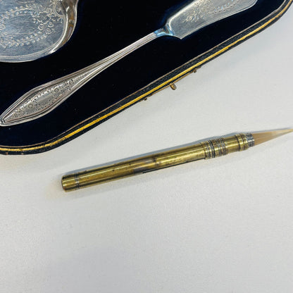 Antique Agate Gold Leaf Burnishing Tool  a natural agate tip lies on a white surface next to its dark velvet case containing engraved silver cutlery.