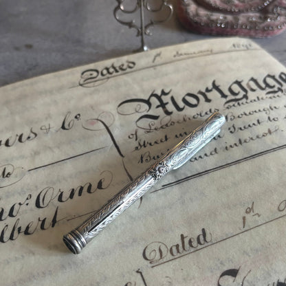 An ornate silver engraved fountain pen resting on an antique-style vintage mortgage document.