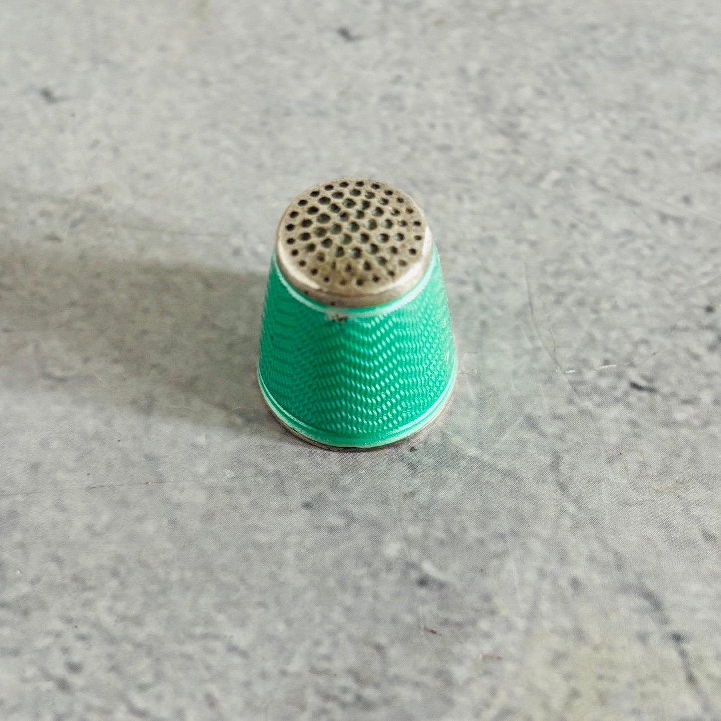 Green thimble on a gray concrete surface