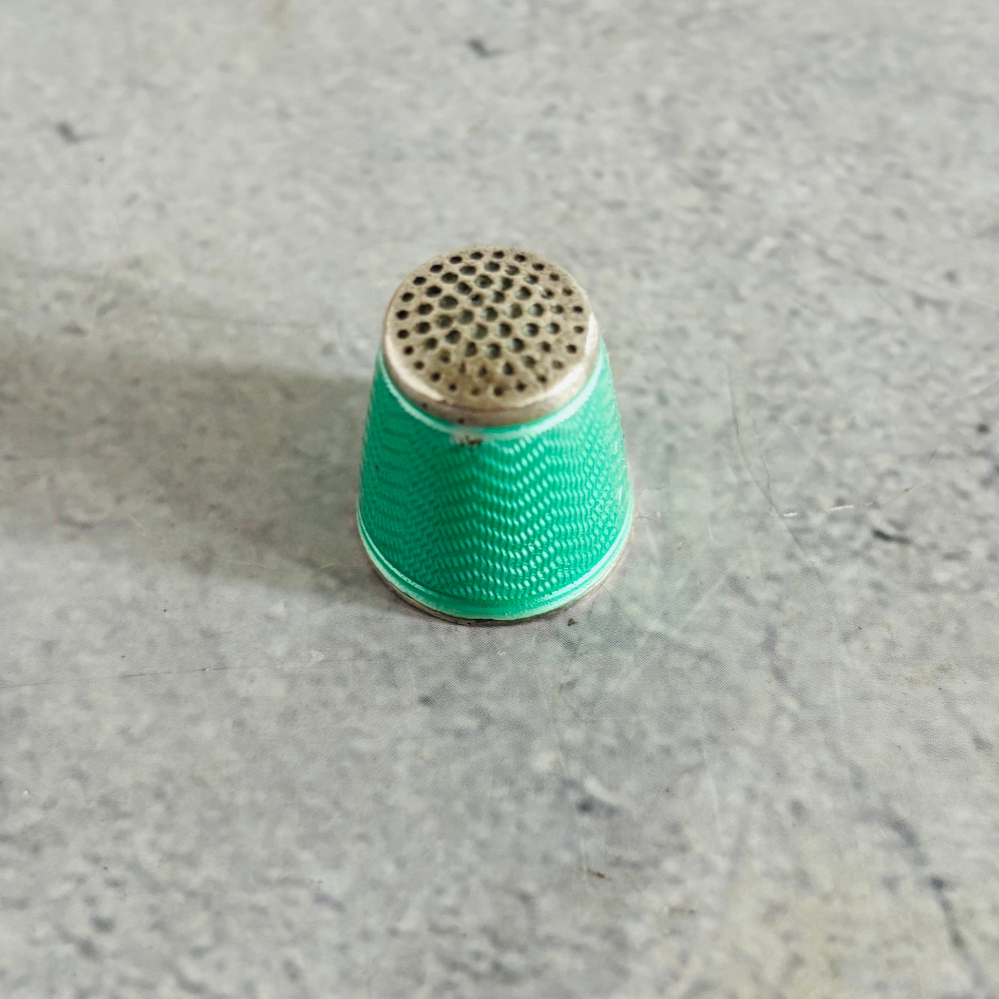 Green thimble on a gray concrete surface