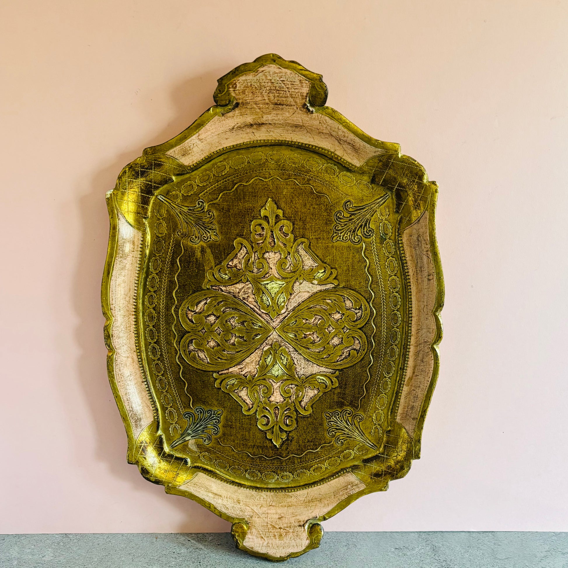 Decorative wall tray with intricate pink and gold design on a plain background